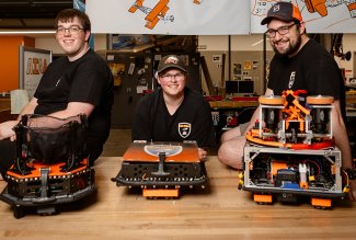Photo of 3 students displaying their robots