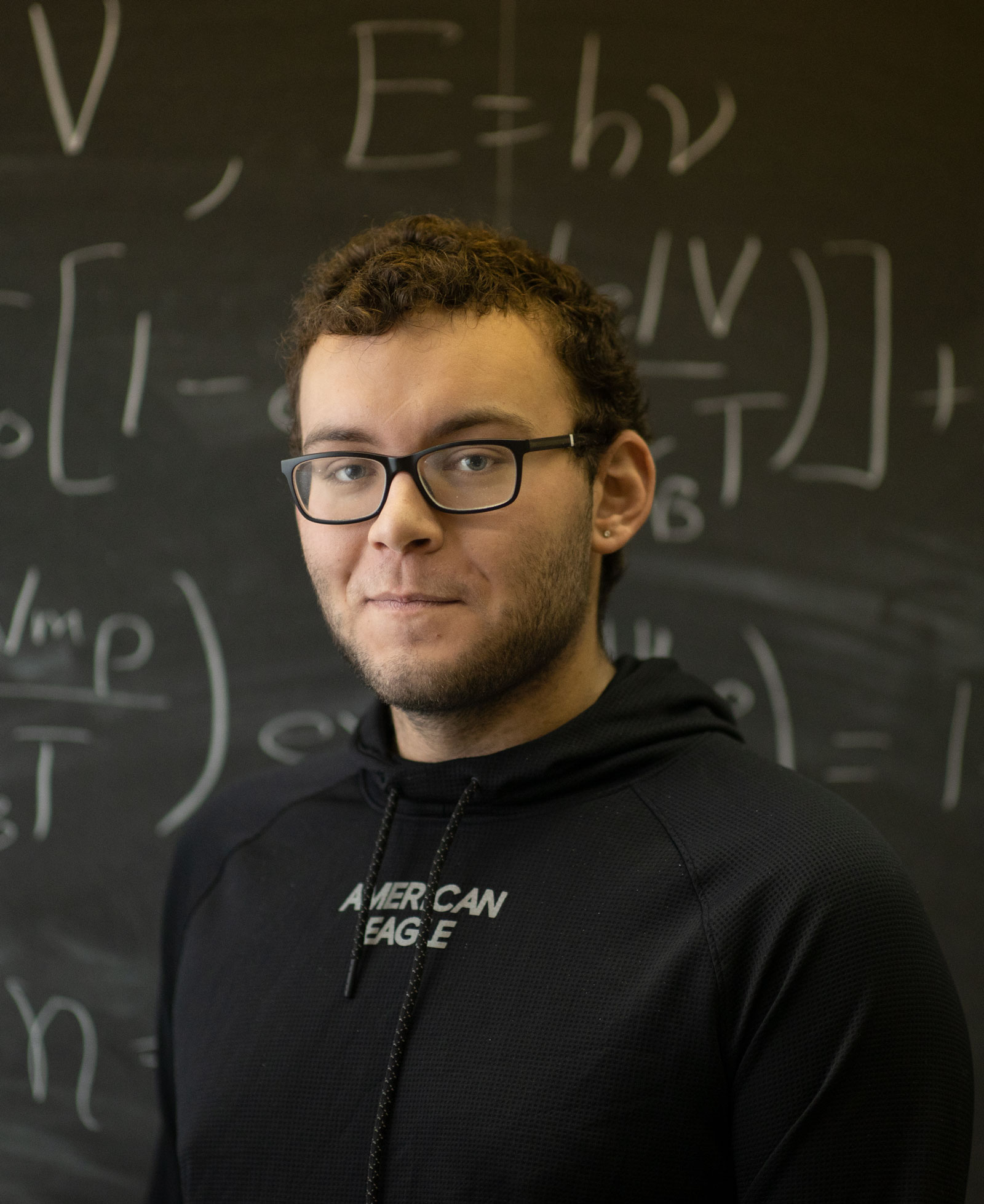 math student pictured in front of equations on a chalkboard.