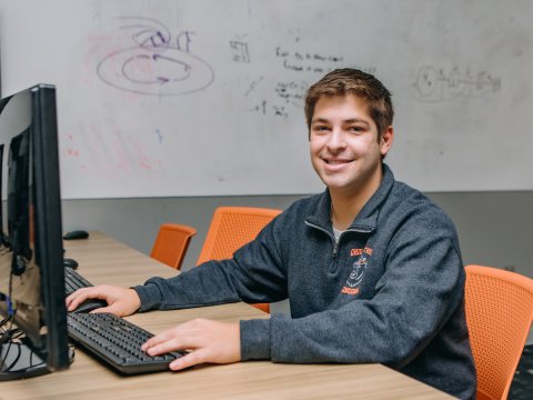 Photo of Alex sitting at a computer