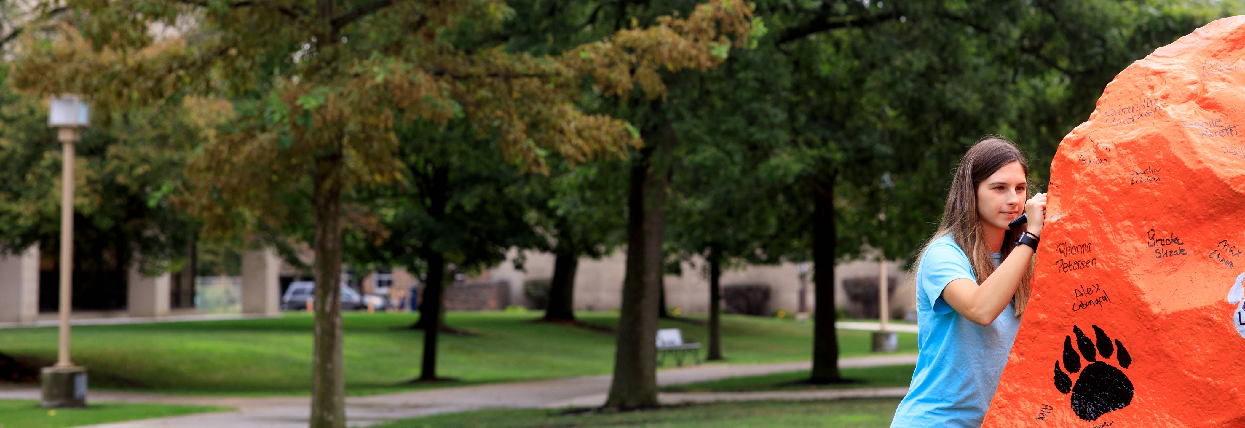 Student signs the Spirit Rock in front of McIntosh Center at Ohio Northern University 