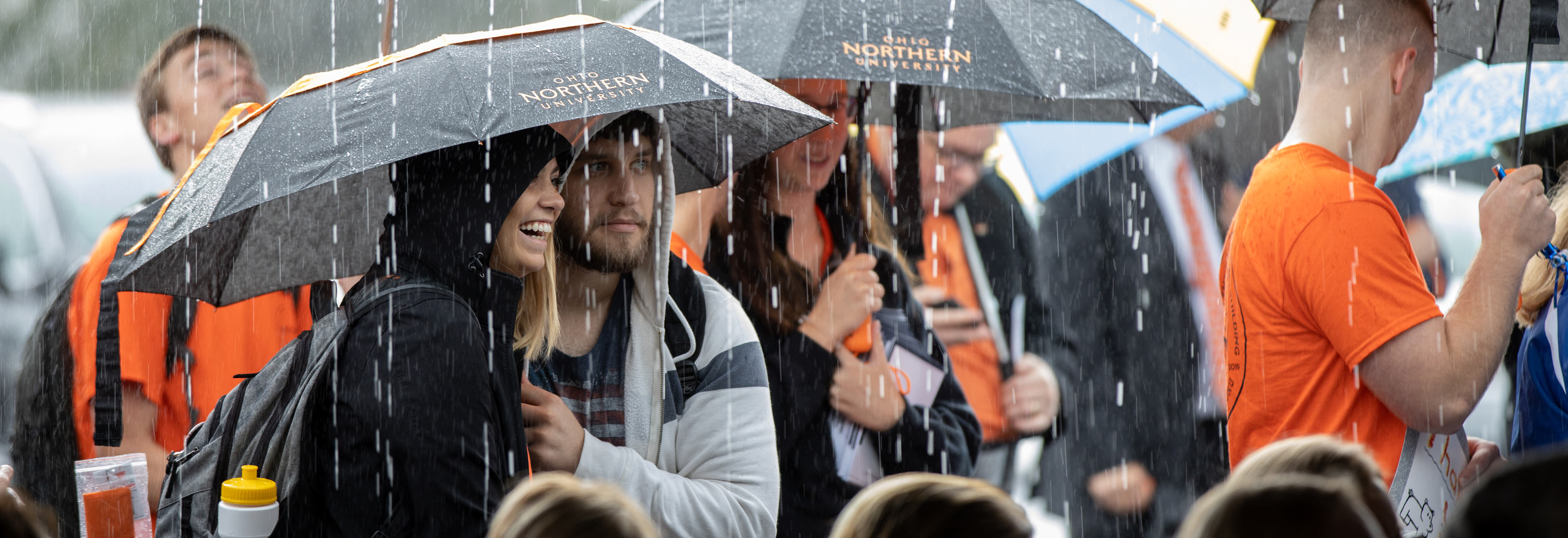 Students laugh outside in the rain