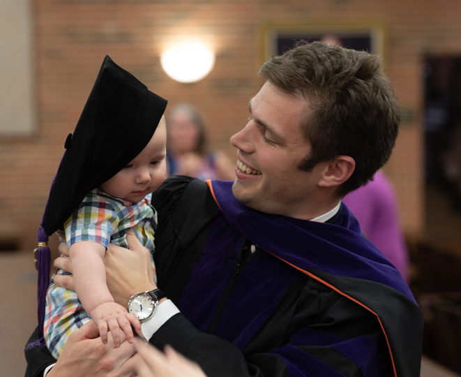 Law graduate holding his child following ceremony