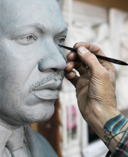 Tad McKillop sculpts the clay form of the bronze sculpture.