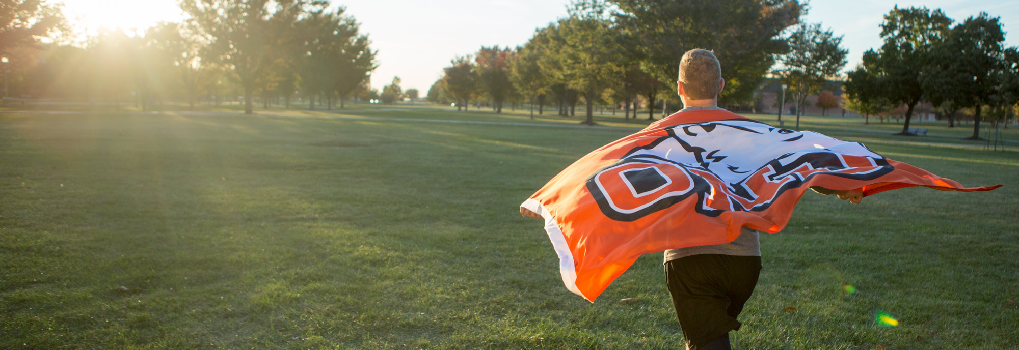 Student running across campus with a flag.