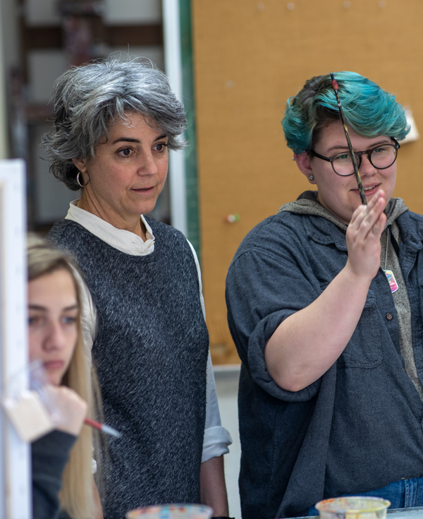 art education student works with a professor in a painting class.