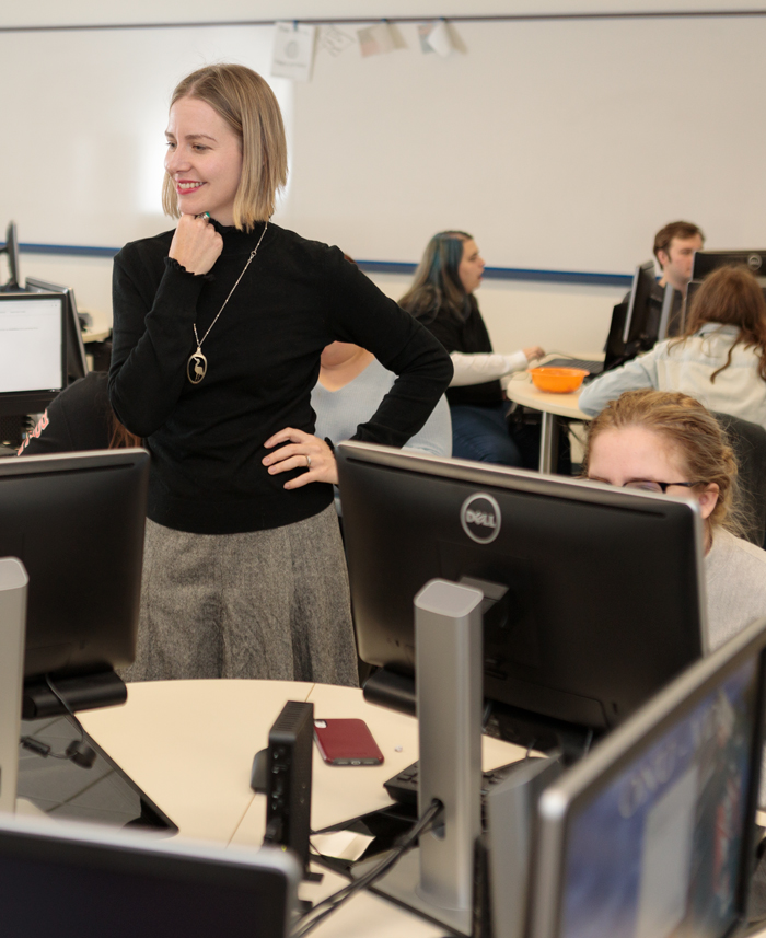 professor works with students in a computer lab during a creative writing exercise. 