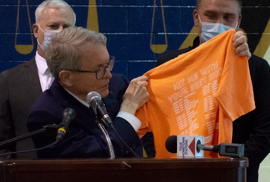 Ohio Governor and ONU alumnus Mike DeWine holds up the vaccination tour T-shirt