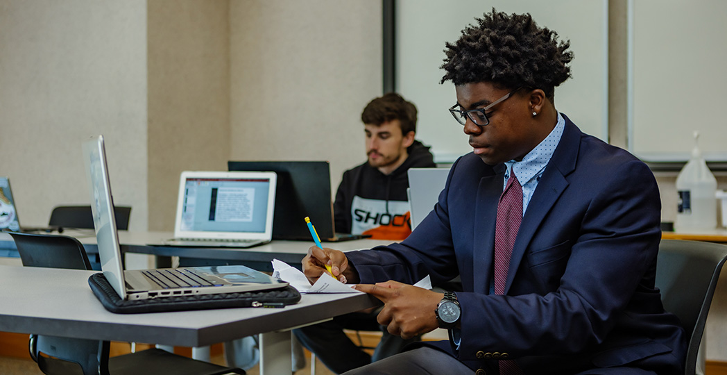 Photo of student in business attire taking notes