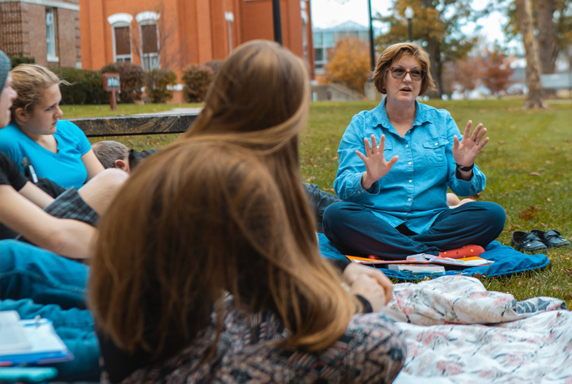 ONU teacher instructing her students on the grass outside