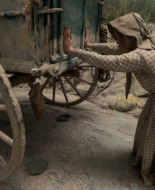 Photo of a person helping out the horses by pushing the wagon