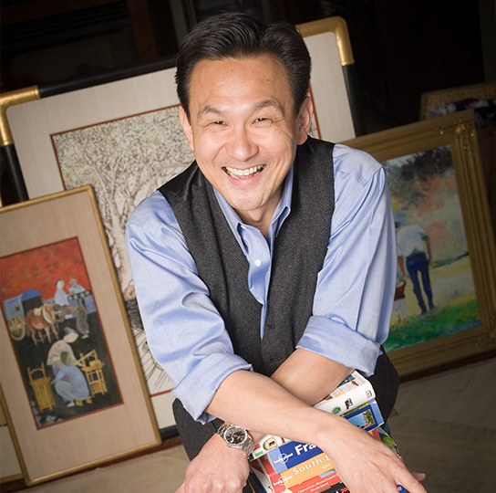 Photo of Ken Lim posing on a stack of books