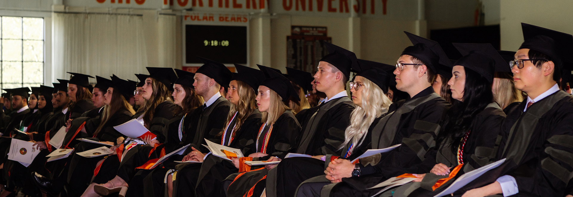 Photo of Graduates sitting in a row watching the ceremony