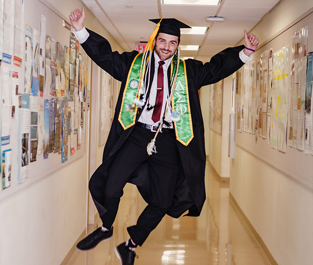 Photo of Quinn in his cap and gown jumping with excitement