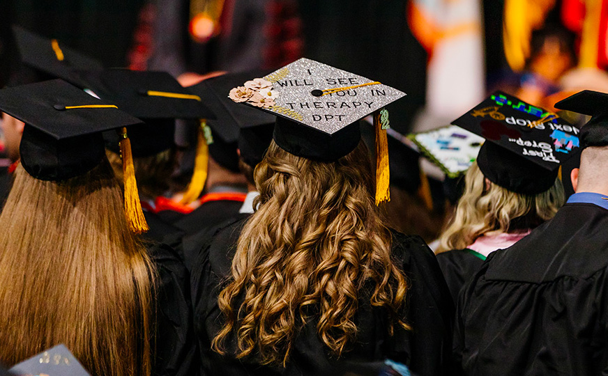 Photo of graduates looking onto the stage from behind