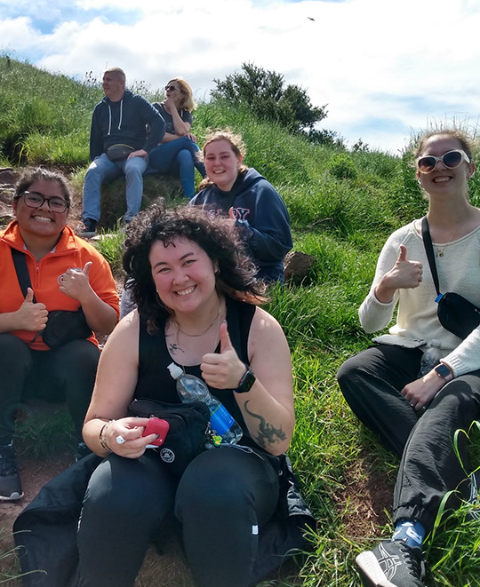 Photo of students sitting on a green grass hill