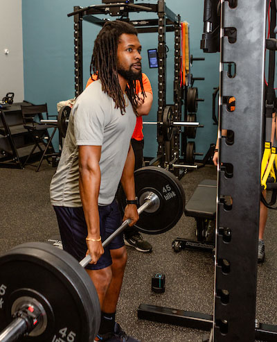 male student lifting bar with weights