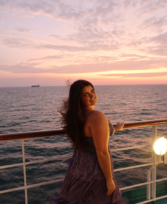 Photo of Mallory standing on the ship deck when the sun goes down