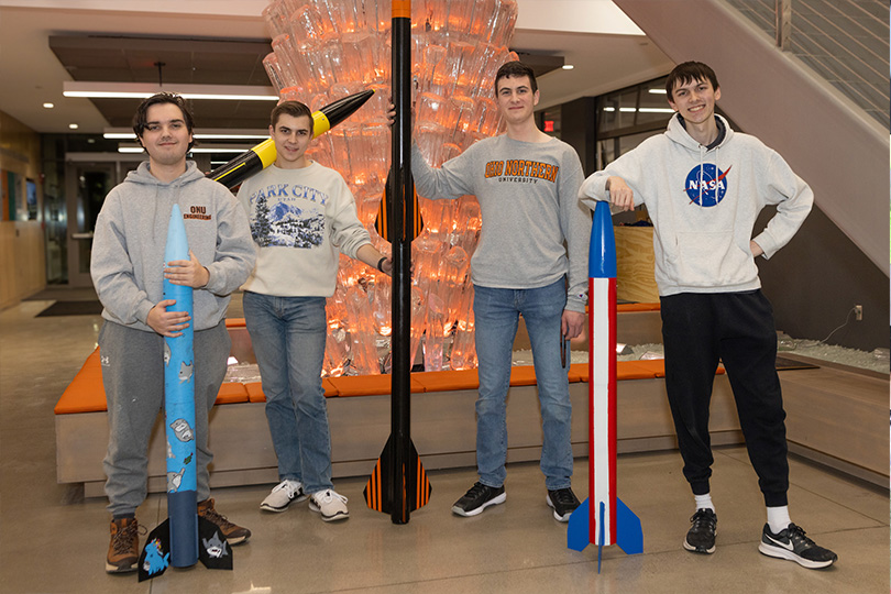 Photo fo 4 ONU students next to their rockets that they made