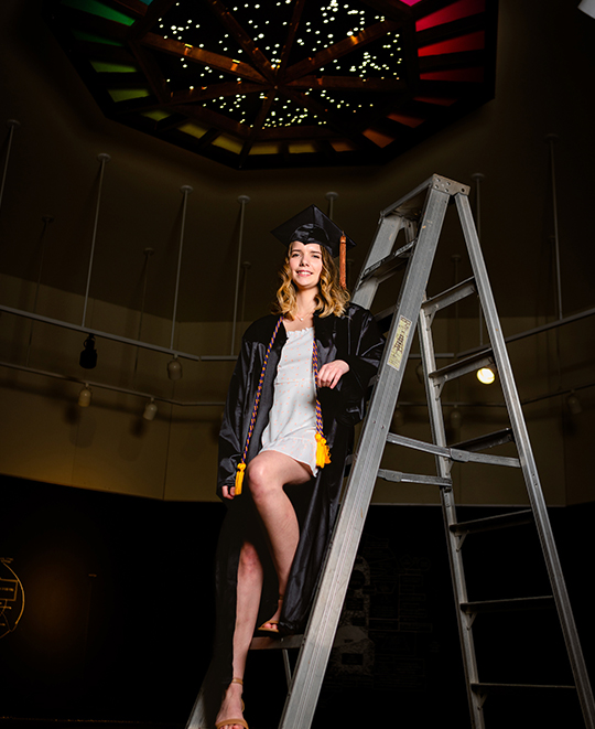 Photo of Lily posing on stage on a ladder