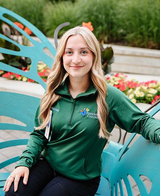 Photo of Ashley sitting on a blue bench shaped like a butterfly