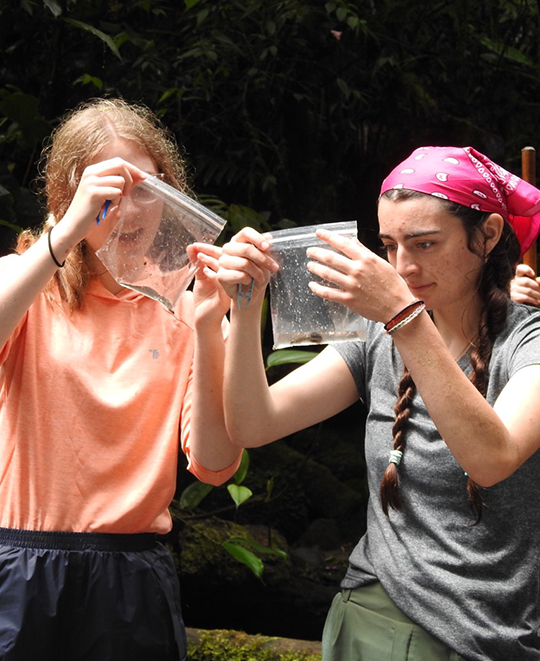 Photo of 2 ONU students holding ziplock bags with a substance as they study it in the air  