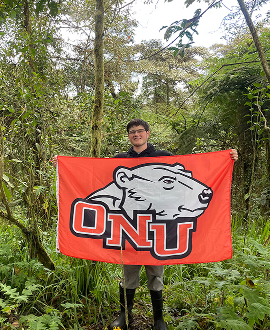 Photo of student holding ONU flag out in the forest