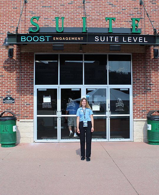 Photo of Chloe standing outside of the Suite enterance