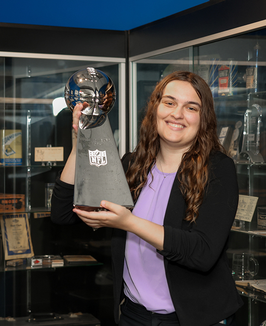 Photo of Ella holding a NFL Vince Lombardi trophey