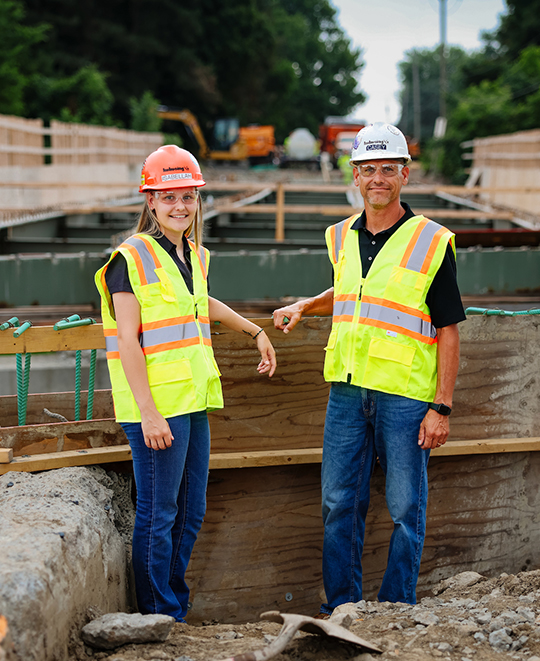 Photo of Isabella with a hard hat on at a work location
