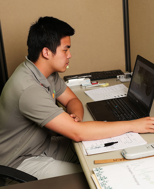 Photo of Long sitting at a desk in front of a laptop