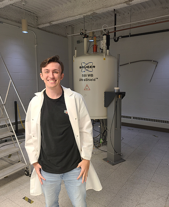 Photo of Max in front of a nuclear magnetic resonance spectroscopy magnet