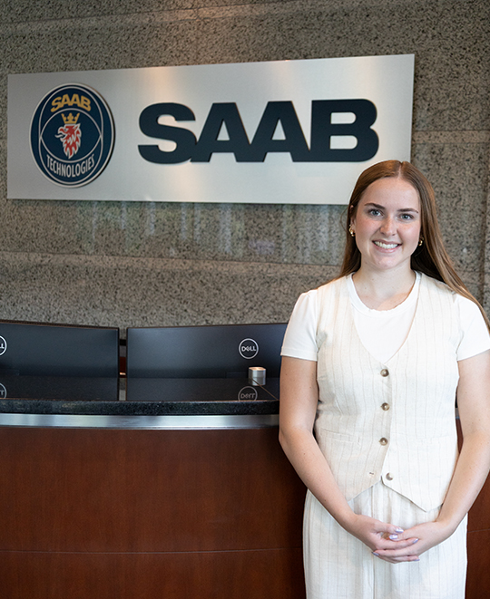 Photo of Rylie standing next to the front desk at SAAB