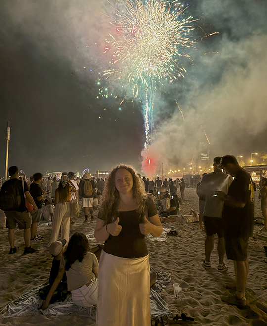 Photo of Emma on the beach with fireworks in the sky in the background