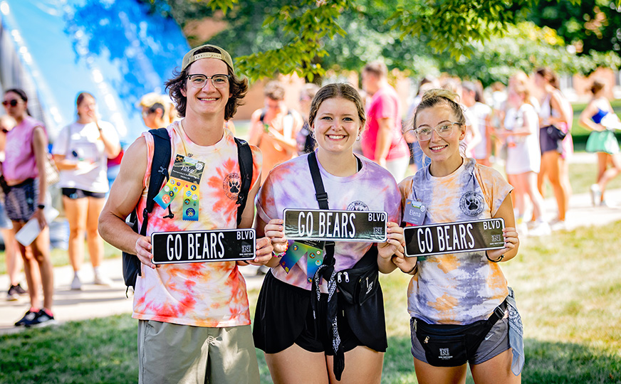 Photo of 3 ONU students holding 'go bears blvd' signs