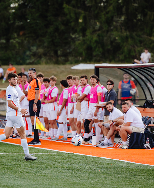 Photo of ONU men soccer player jogging close to our own sidelines with the rest of the team in the background watching