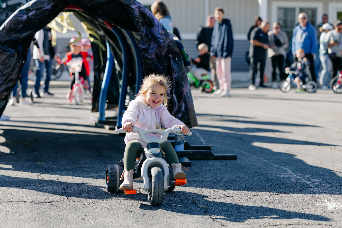 A small child riding a tricycle in a parking lot