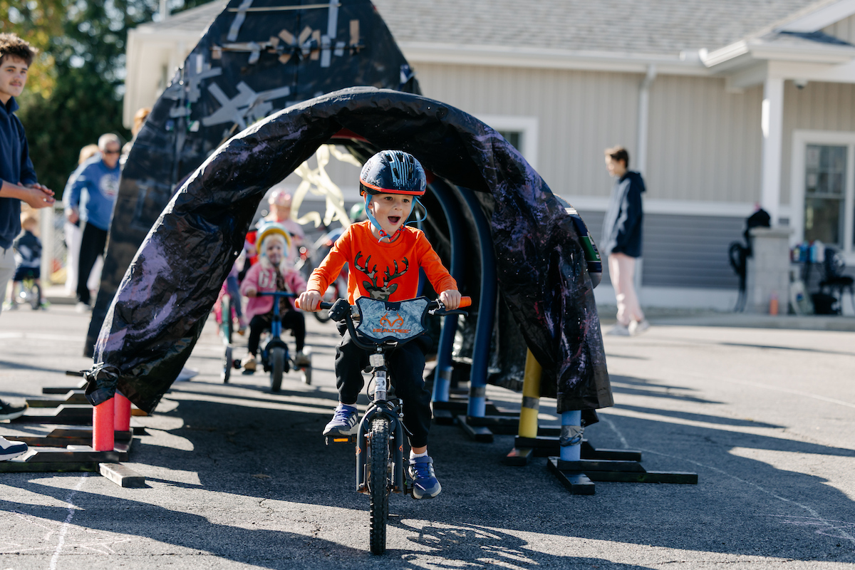 A small child riding a bicycle through a tunnel in a parking lot