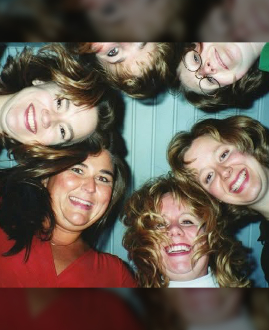 Photo of the group when in college looking down on the camera in a huddle