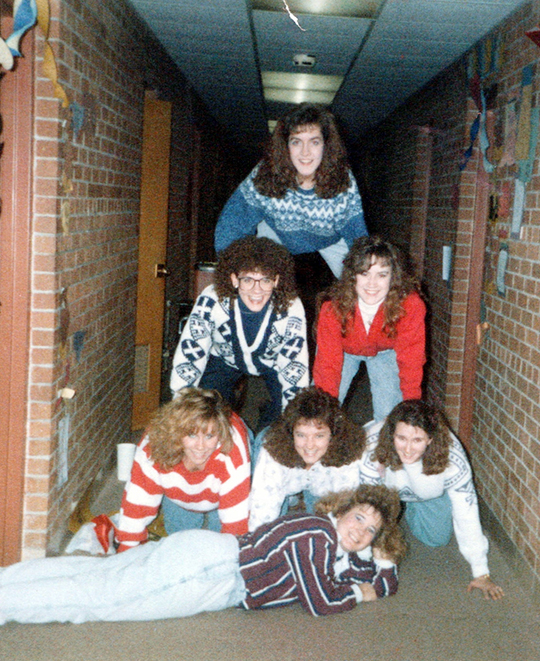 Photo of the friends in their college days building a human pyramid in the dorm hallway