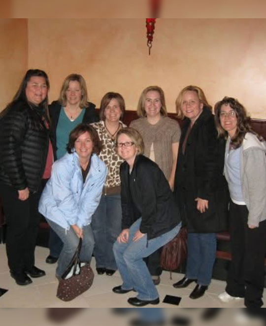 Group photo of 8 friends posing together after a dinner together