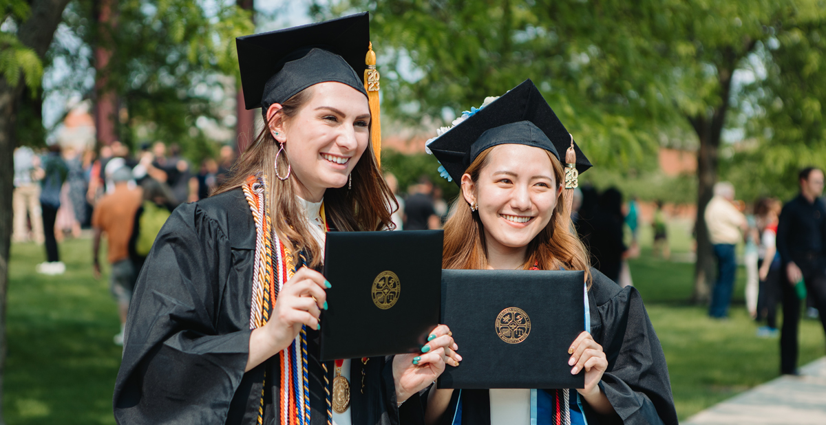 female graduates smiling and holding their diplomas