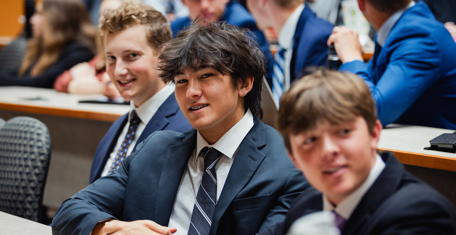 male student in a suit listening to a lecture