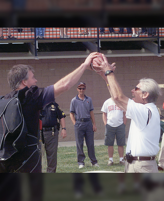 Photo of Baker handing off a football to another person