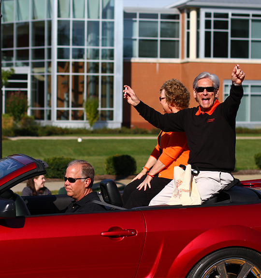 Photo of Dr. Baker and his wife seated in a red convertable 