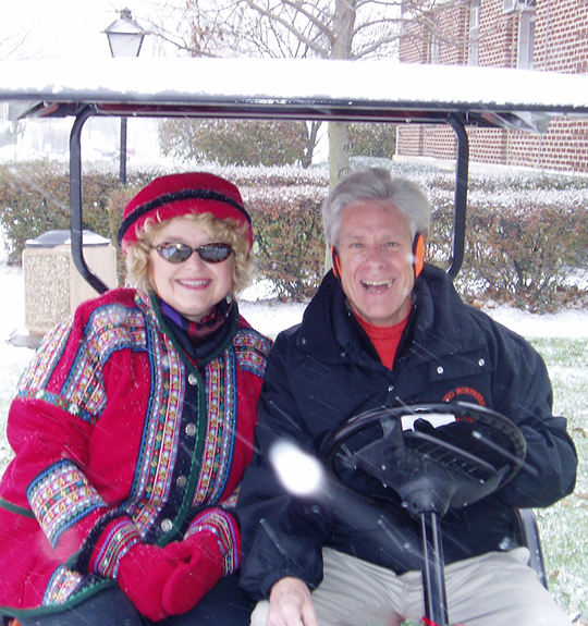 Photo of Dr. Baker and his wife dressed warm in a golf cart out in the snow