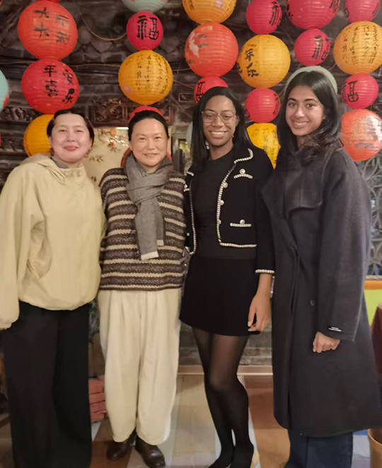 Group of 4 posing in front of orange and red circular paper decorations 