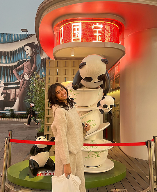 Samran posing in front of statue of teacups with pandas on them