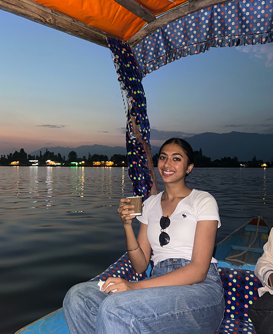 India photo out on the water on a boat, Simran posing with a cup in her hand