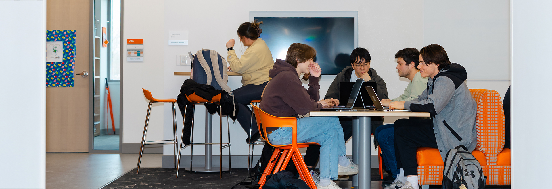 6 ONU students gathered around a table in an engineering room working or discussing projects 