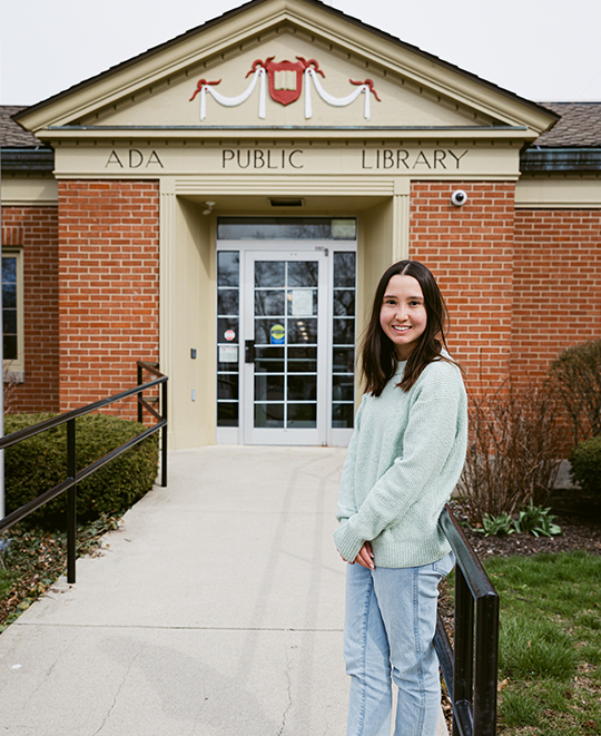 Eva leaning against railing outside of the Ada Public Library